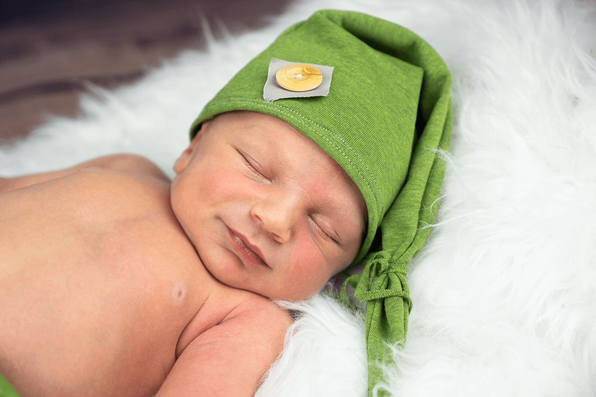 Baby schläft mit grüner Mütze